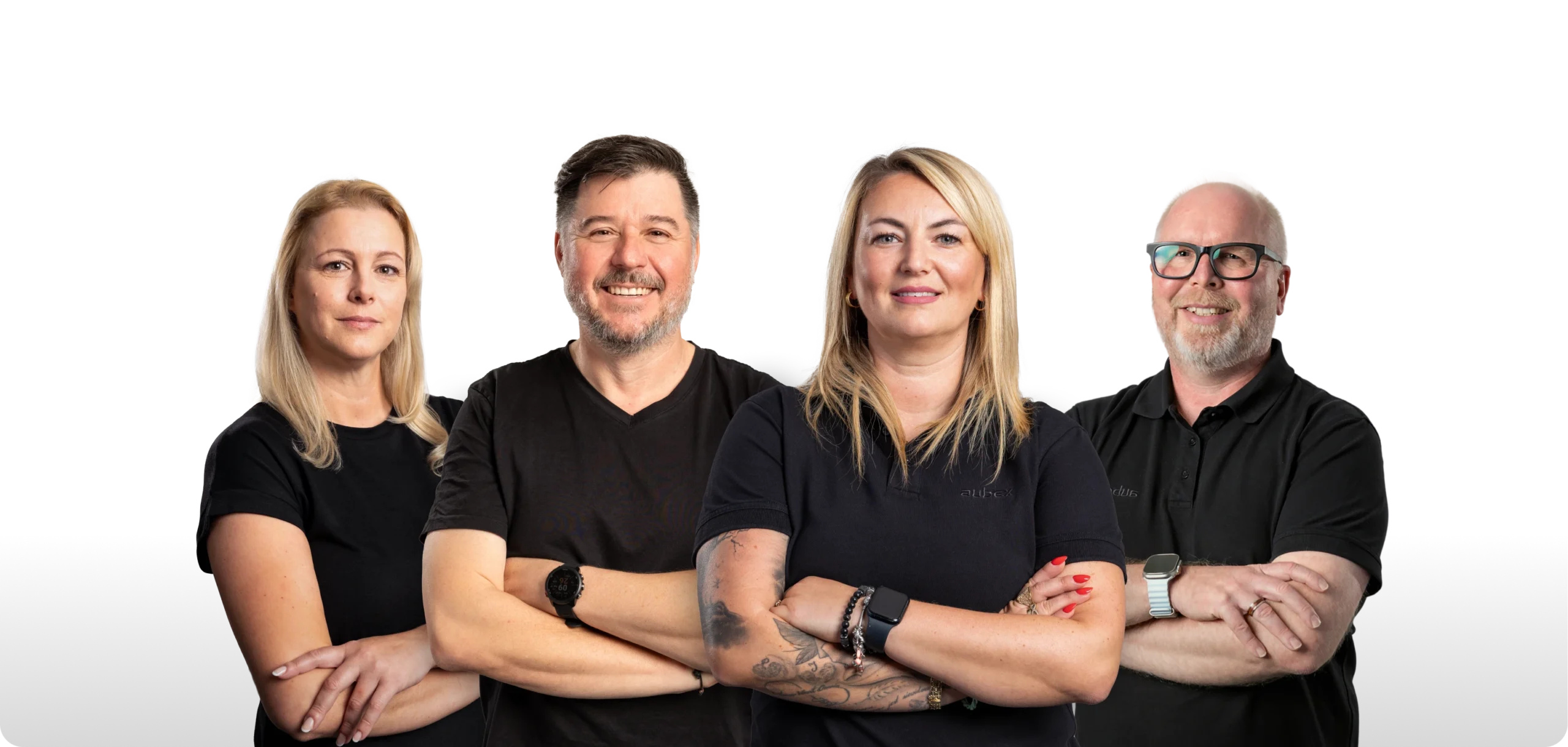 Eine Gruppe von neun Personen steht nebeneinander und lächelt in die Kamera. Alle tragen dunkle Kleidung, einige mit Firmenlogos auf den Shirts.